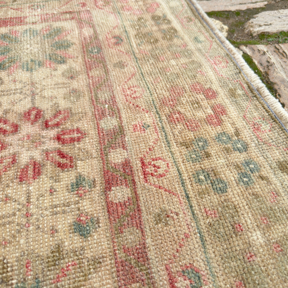 Close-up of the pink vintage turkish rug showing medallion details, hand-knotted weave, wool and cotton and low pile.