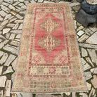 Pink 4' x 7' vintage turkish rug in wool and cotton, shown on the floor.