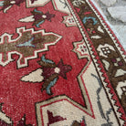 Close-up of the red vintage turkish rug showing medallion details, hand-knotted weave, wool and cotton and low pile.