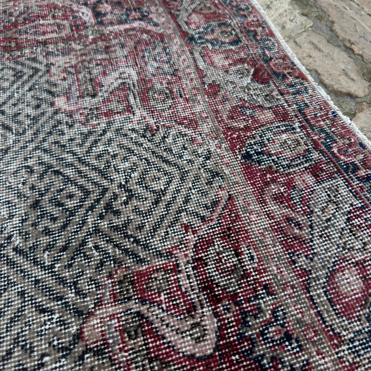Close-up of the red vintage turkish rug showing medallion details, hand-knotted weave, wool and cotton and low pile.