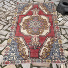 Red 4' x 7' vintage turkish rug in wool and cotton, shown on the floor.