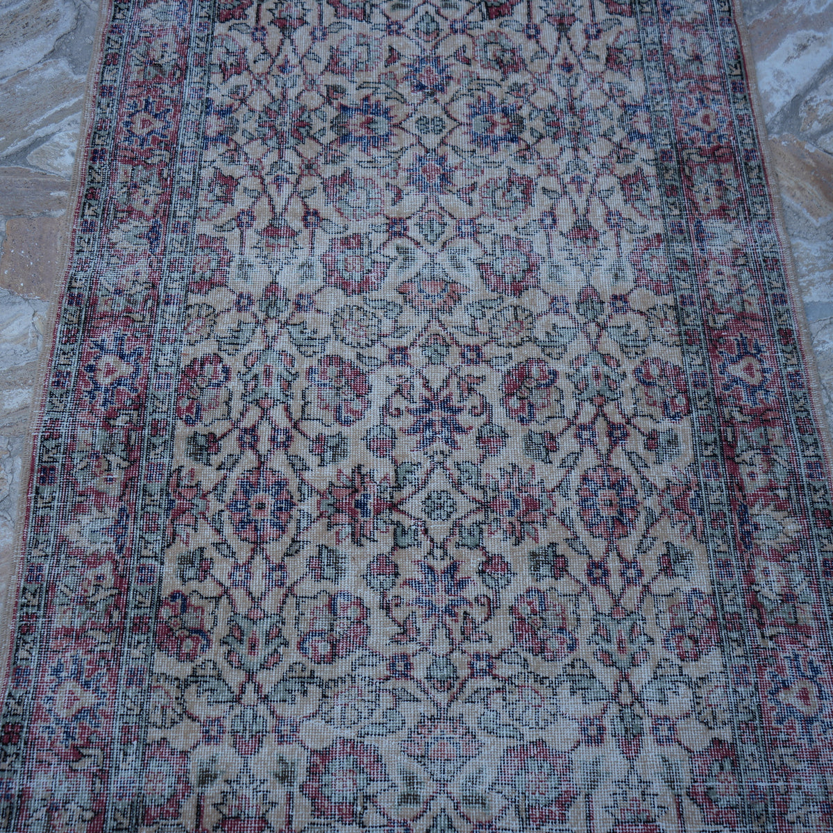 Close-up of the red vintage turkish rug showing floral details, hand-knotted weave, wool and cotton and low pile.