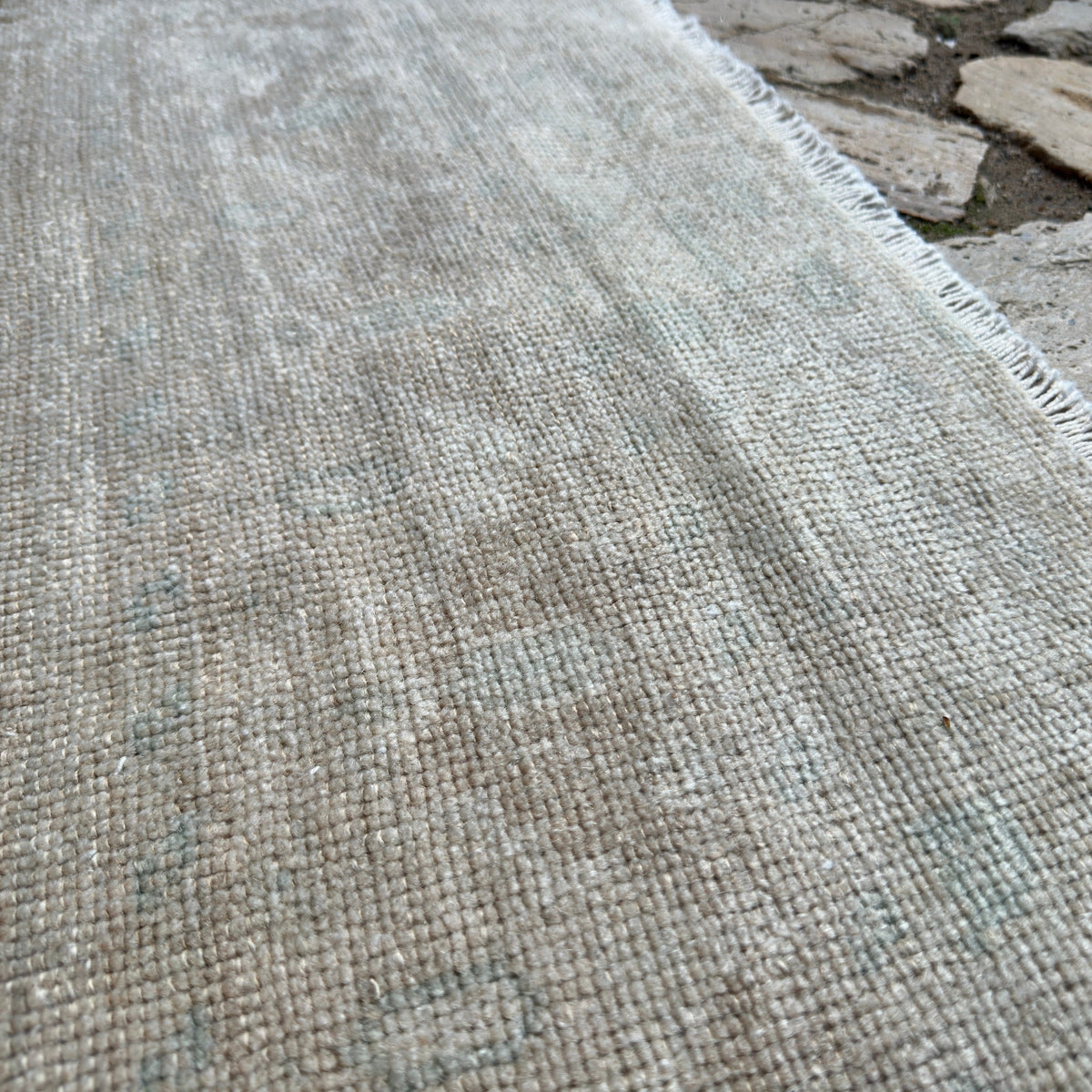 Close-up of the beige vintage turkish rug showing neutral details, hand-knotted weave, wool and cotton and low pile.