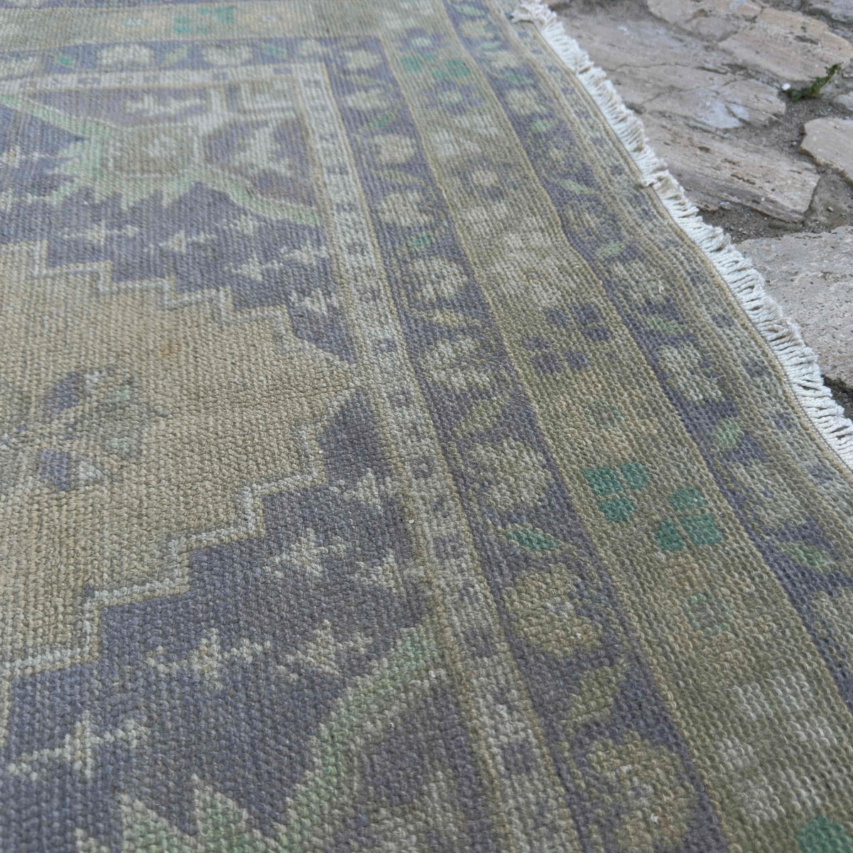 Close-up of the beige vintage turkish rug showing traditional details, hand-knotted weave, wool and cotton and low pile.