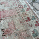 Close-up of the pale pink vintage turkish rug showing traditional details, hand-knotted weave, wool and cotton and low pile.