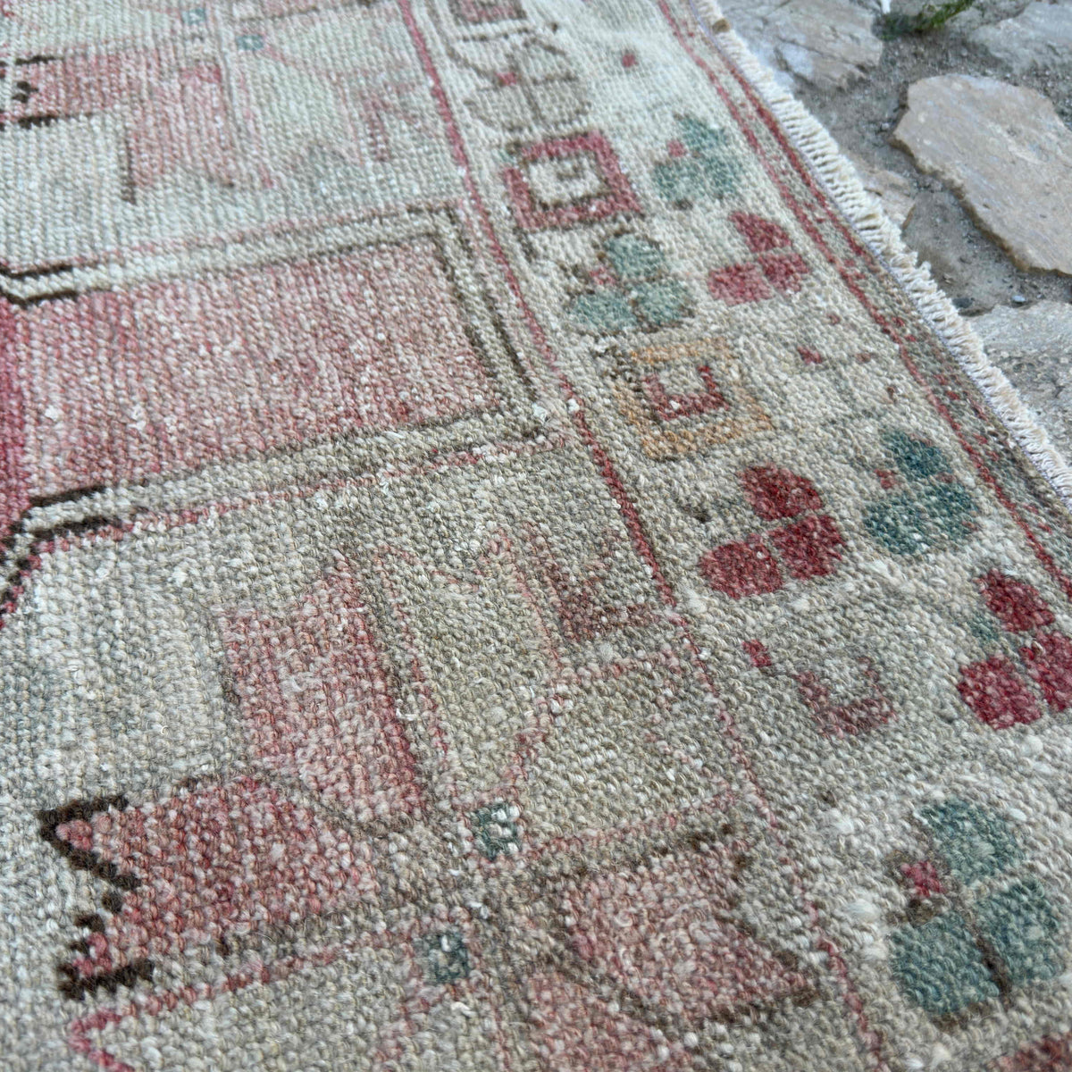 Close-up of the pale pink vintage turkish rug showing traditional details, hand-knotted weave, wool and cotton and low pile.