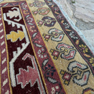 Close-up of the red vintage turkish rug showing geometric details, hand-knotted weave, wool and cotton and low pile.