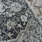 Close-up of the black vintage turkish rug showing neutral details, hand-knotted weave, wool and cotton and low pile.