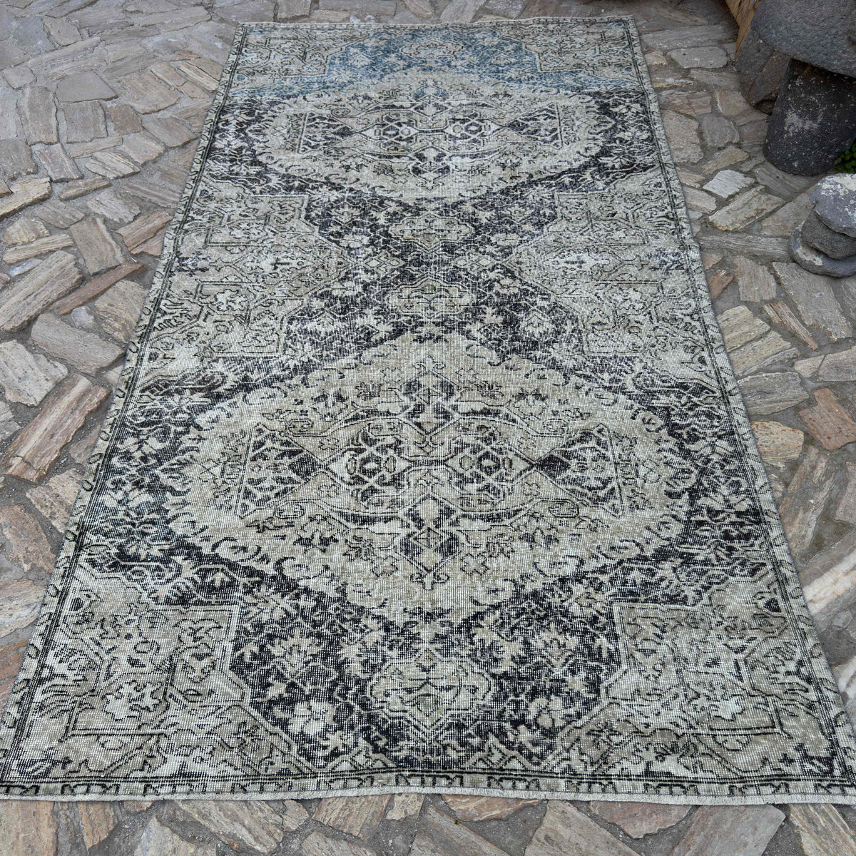 Black 5' x 10' vintage turkish rug in wool and cotton, shown on the floor.