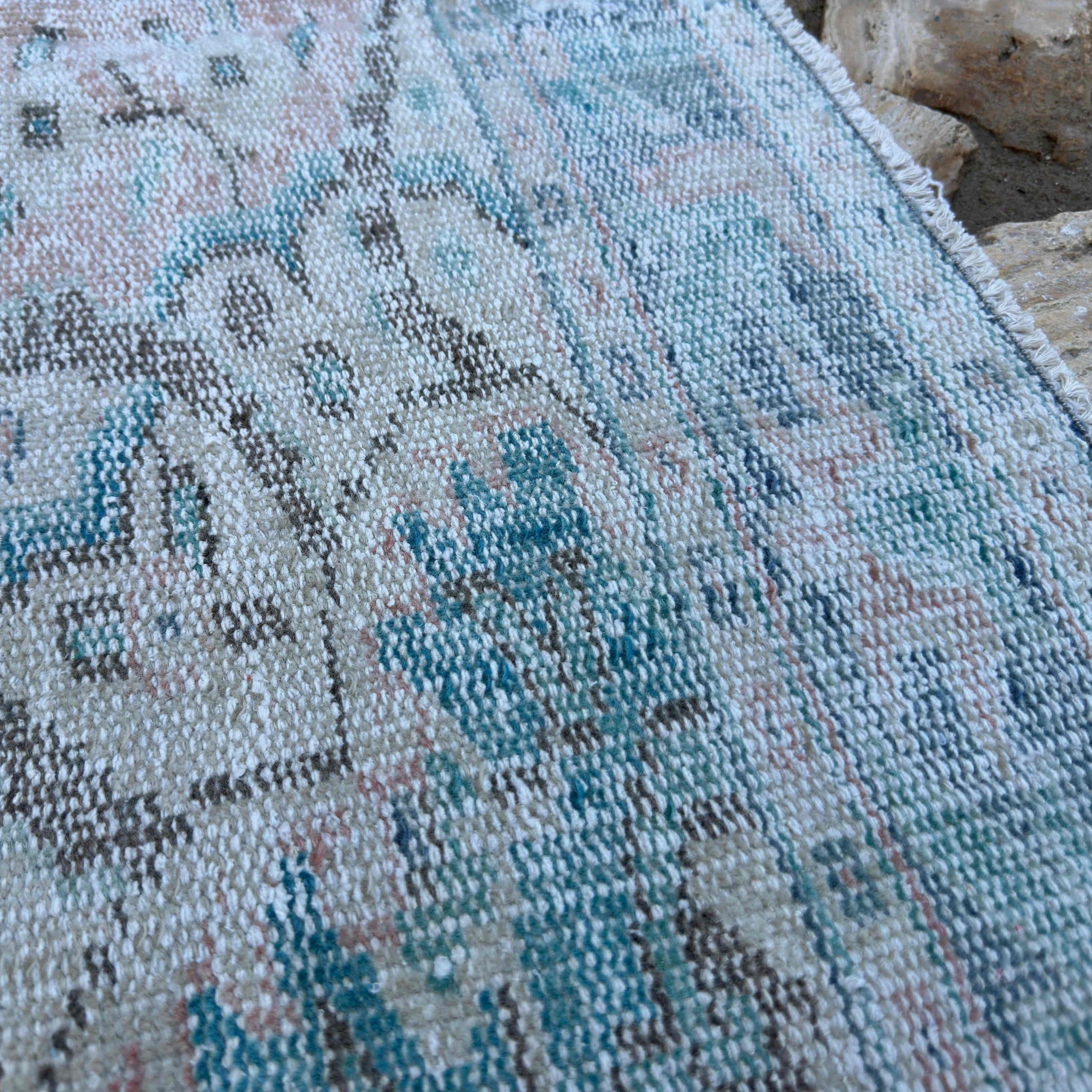 Close-up of the pink vintage turkish rug showing medallion details, hand-knotted weave, wool and cotton and low pile.