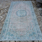 Pink 5' x 10' vintage turkish rug in wool and cotton, shown on the floor.