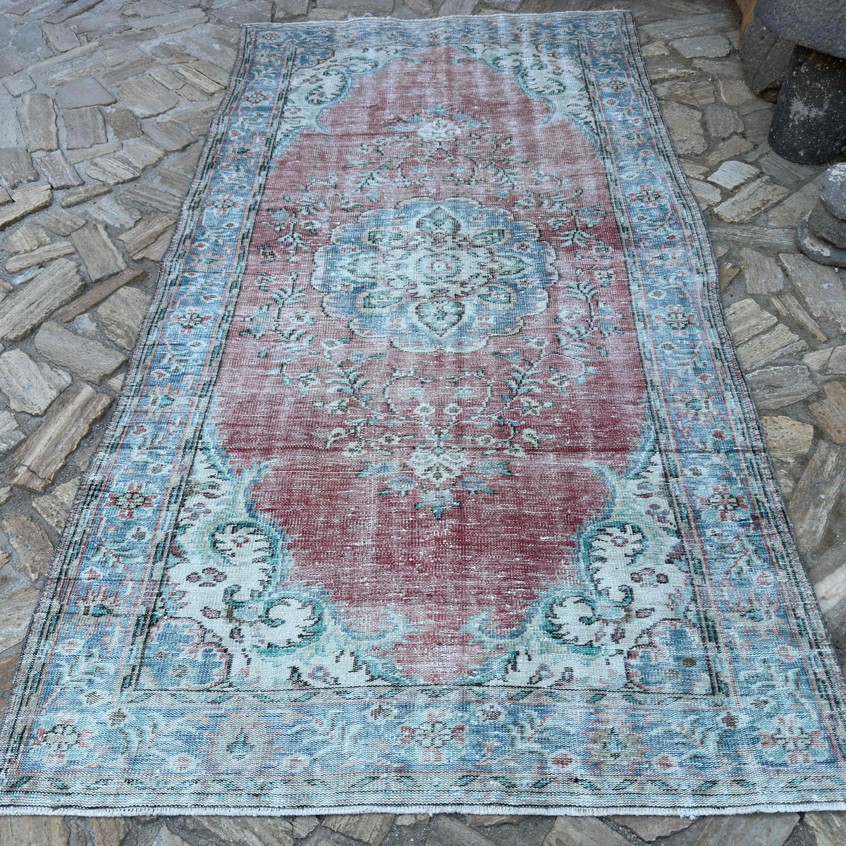 Red 5' x 10' vintage turkish rug in wool and cotton, shown on the floor.