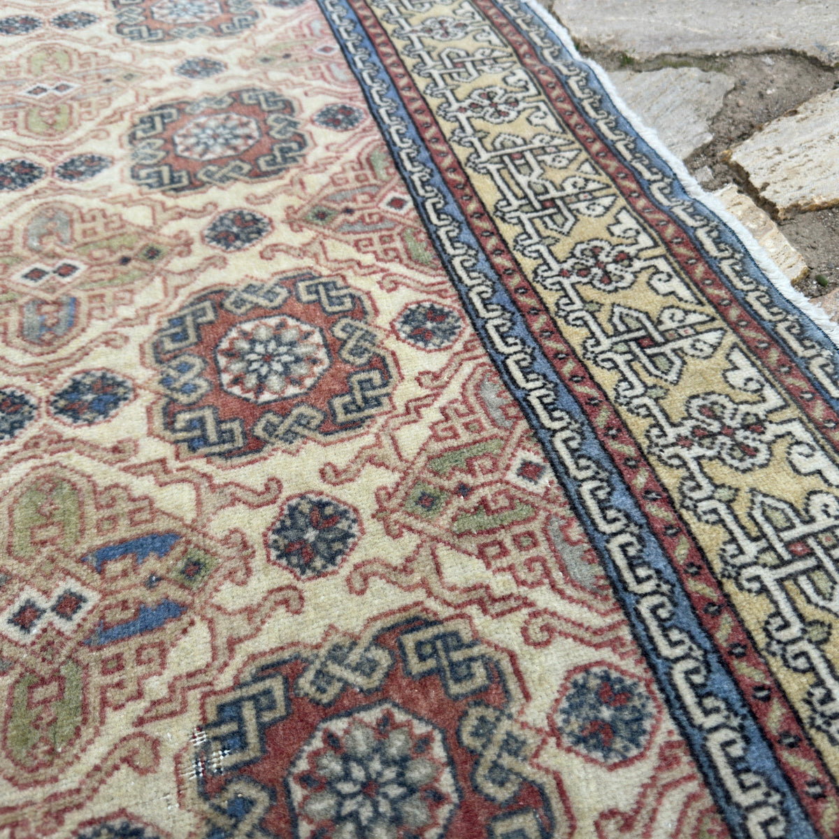 Close-up of the pale red vintage turkish rug showing traditional details, hand-knotted weave, wool and cotton and low pile.