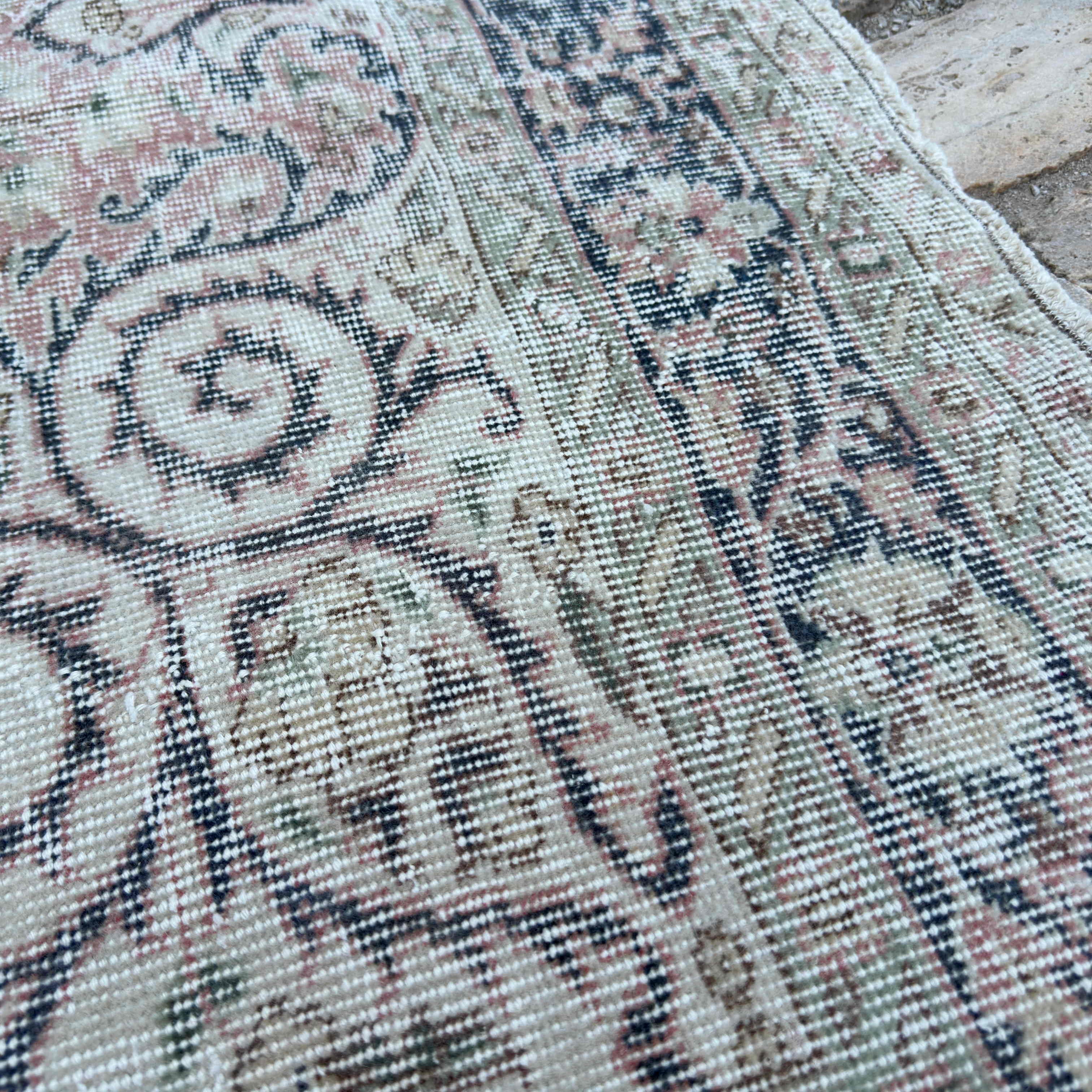 Close-up of the pink vintage turkish rug showing medallion details, hand-knotted weave, wool and cotton and low pile.