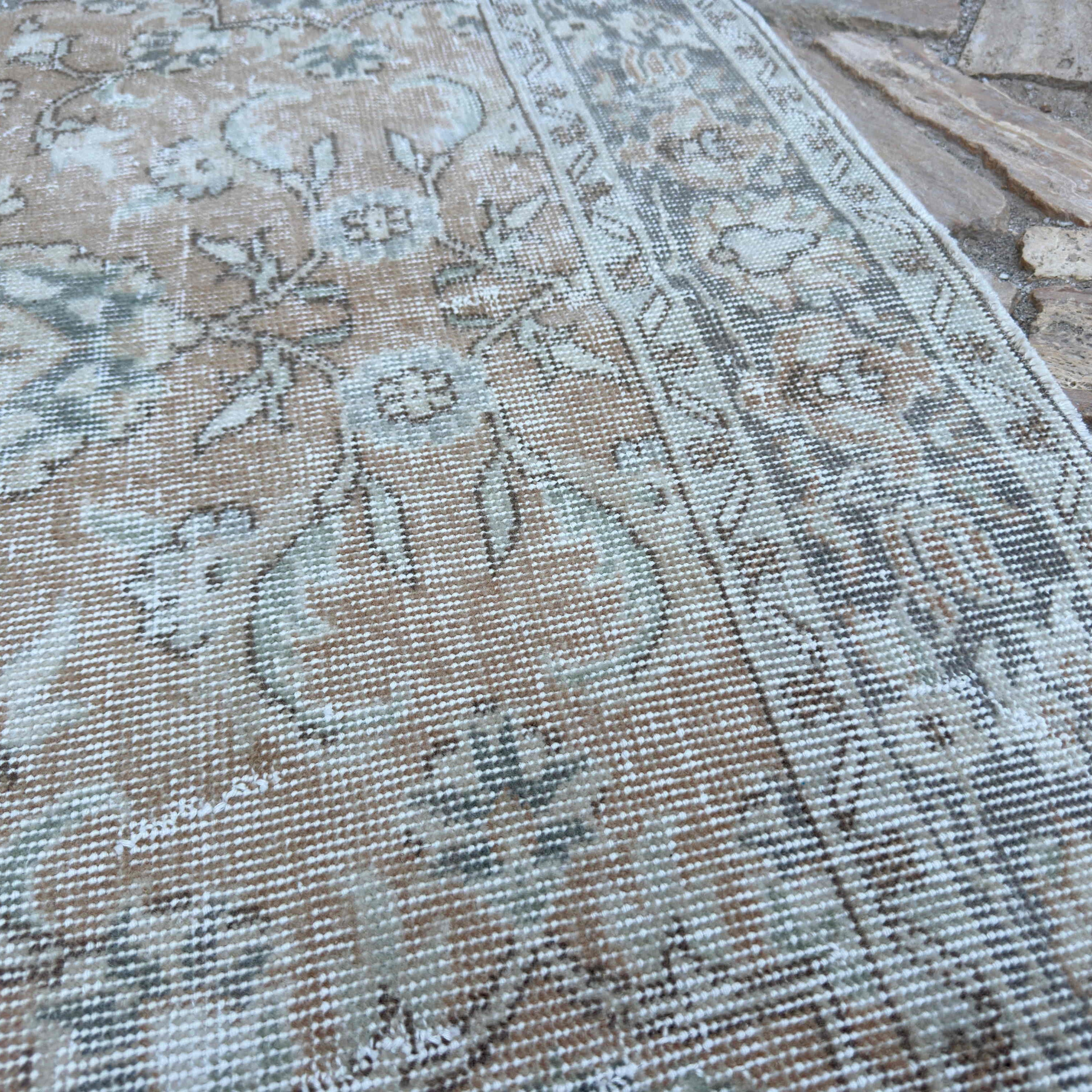 Close-up of the beige vintage turkish rug showing floral details, hand-knotted weave, wool and cotton and low pile.