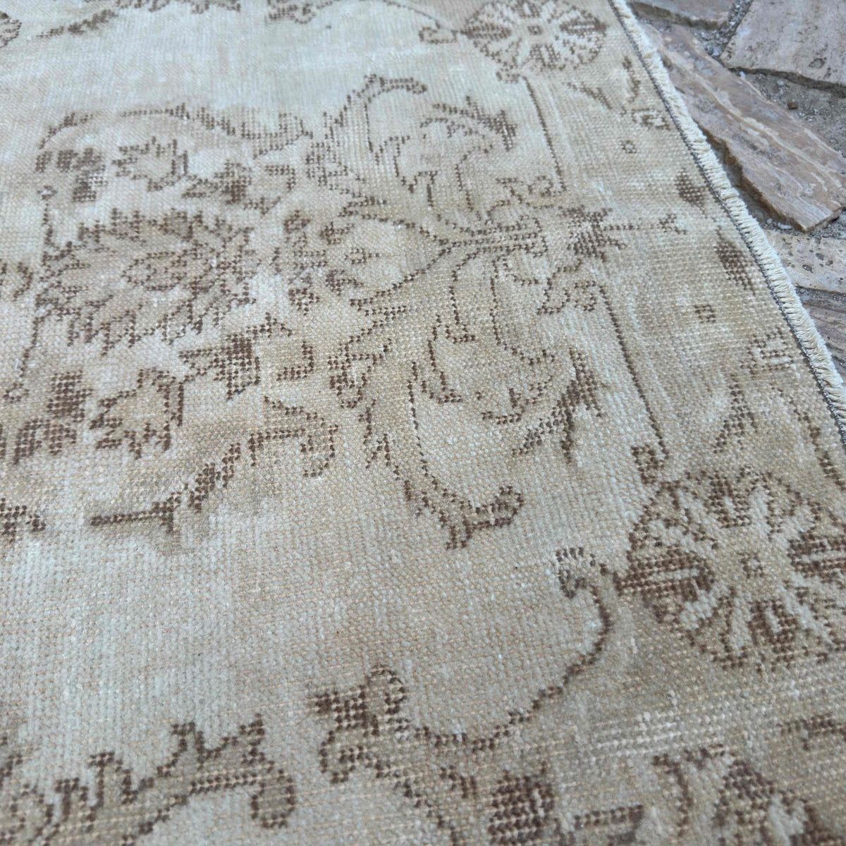 Close-up of the beige vintage turkish rug showing neutral details, hand-knotted weave, wool and cotton and low pile.