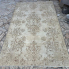 Beige 5' x 9' vintage turkish rug in wool and cotton, shown on the floor.