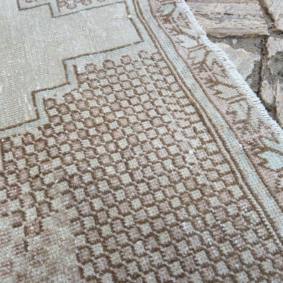 Close-up of the brown vintage turkish rug showing geometric details, hand-knotted weave, wool and cotton and low pile.