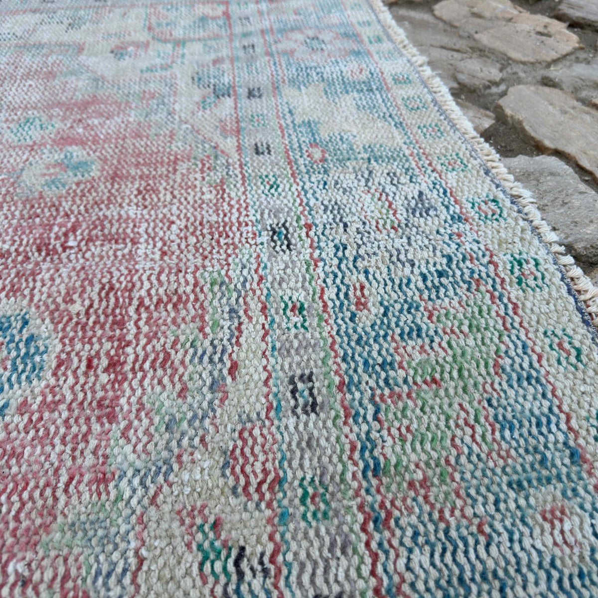 Close-up of the red vintage turkish rug showing medallion details, hand-knotted weave, wool and cotton and low pile.