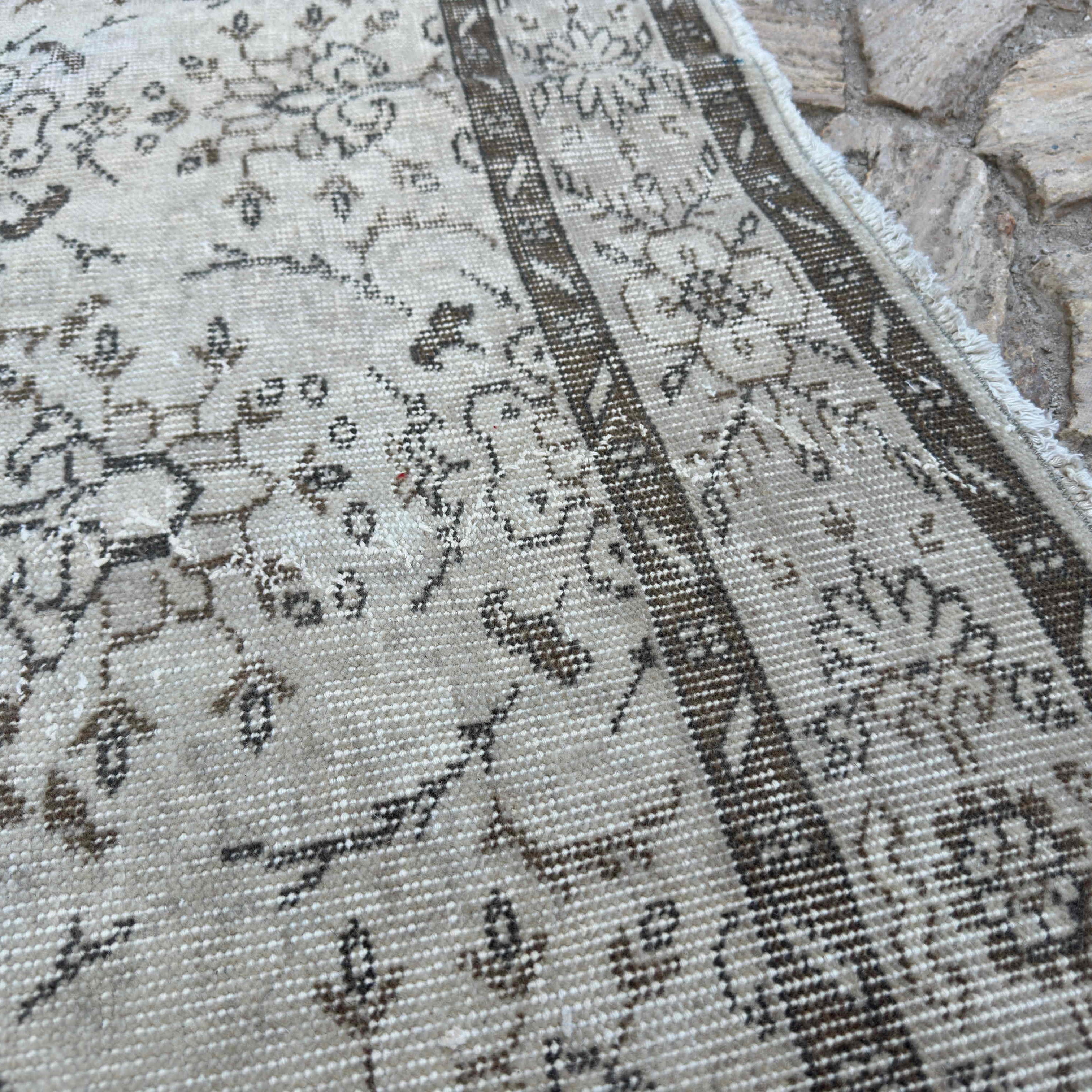 Close-up of the beige vintage turkish rug showing floral details, hand-knotted weave, wool and cotton and low pile.