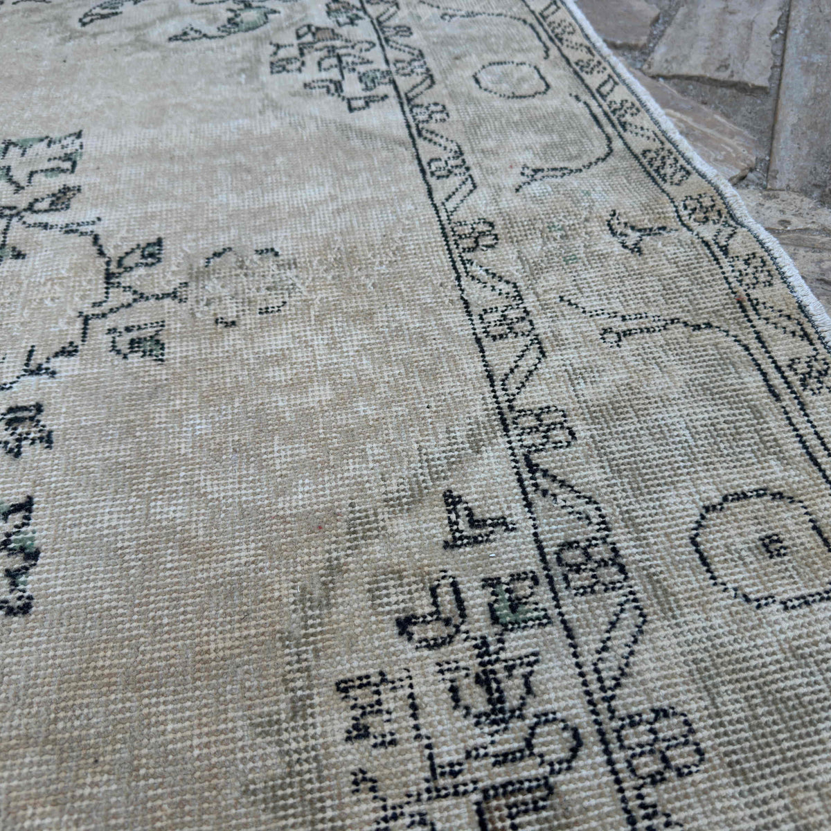 Close-up of the beige vintage turkish rug showing medallion details, hand-knotted weave, wool and cotton and low pile.