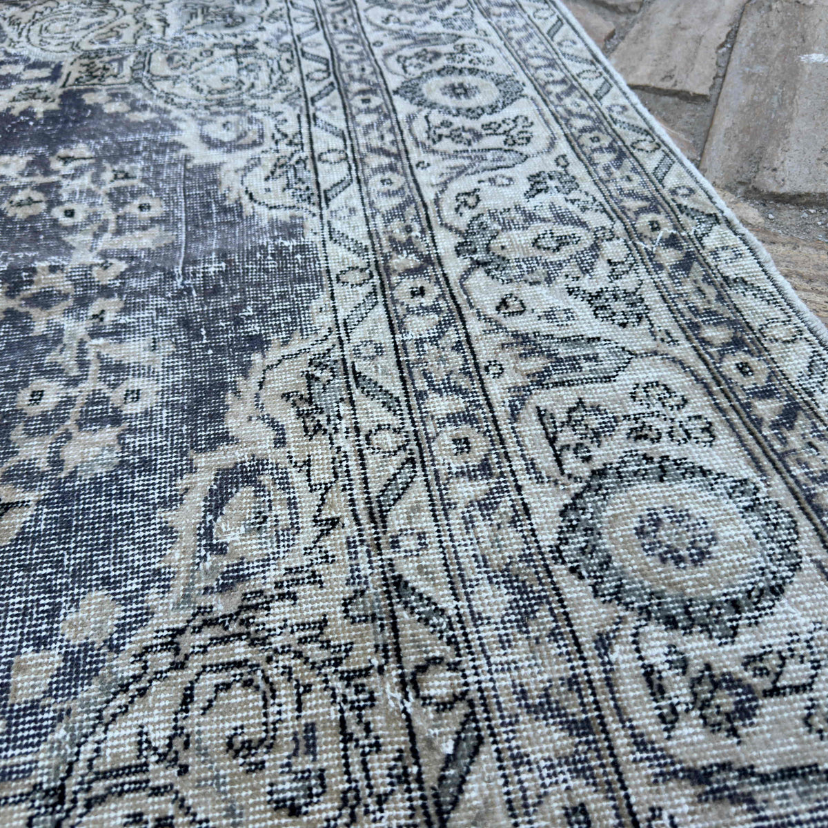Close-up of the beige vintage turkish rug showing medallion details, hand-knotted weave, wool and cotton and low pile.