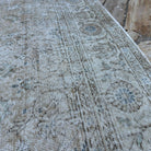 Close-up of the beige vintage turkish rug showing floral details, hand-knotted weave, wool and cotton and low pile.