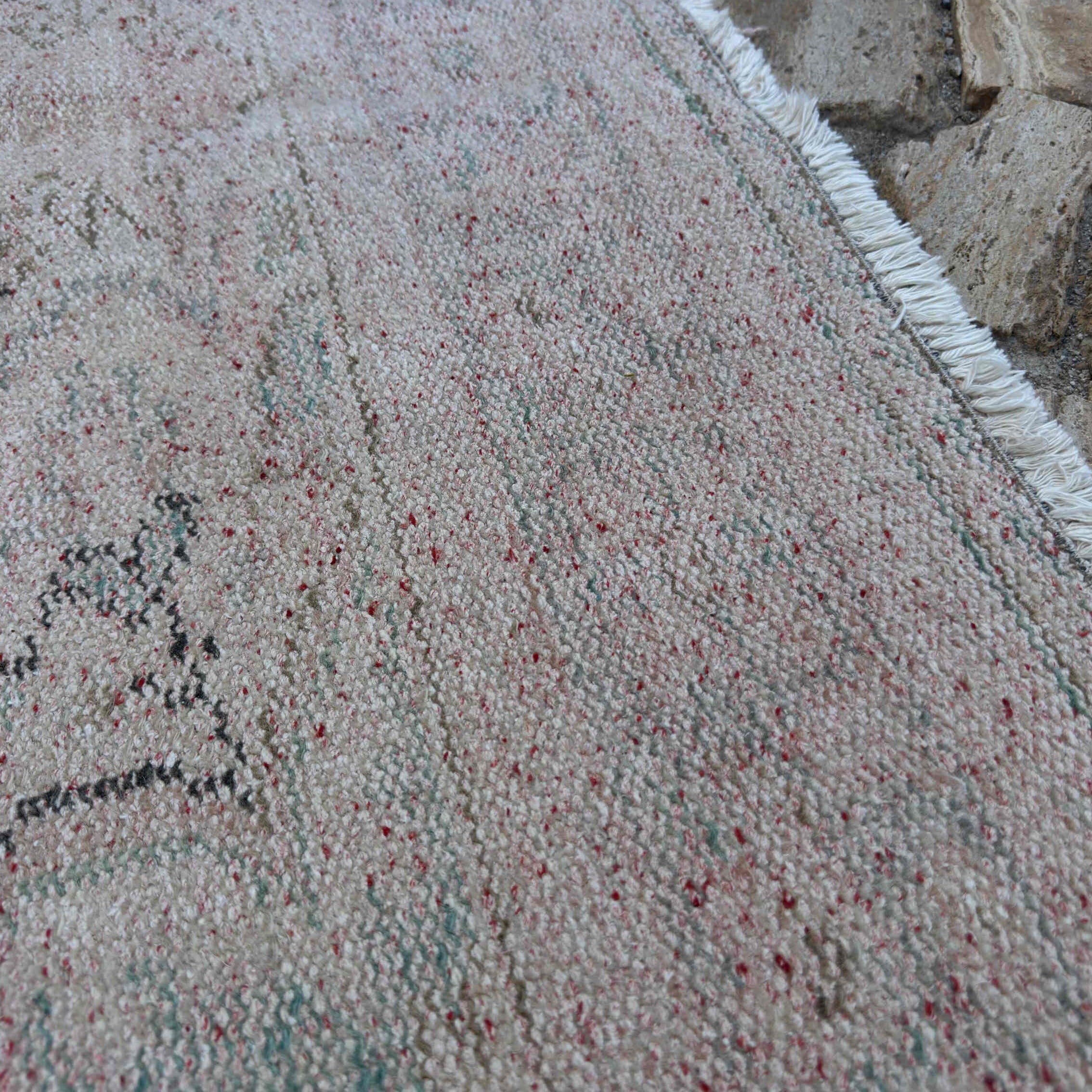 Close-up of the beige vintage turkish rug showing medallion details, hand-knotted weave, wool and cotton and low pile.