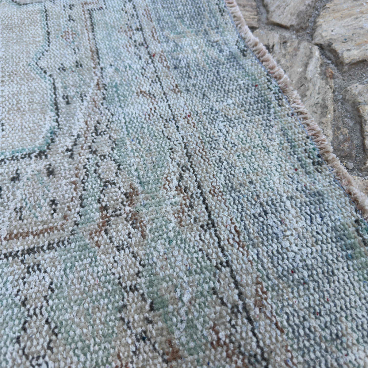 Close-up of the beige vintage turkish rug showing neutral details, hand-knotted weave, wool and cotton and low pile.