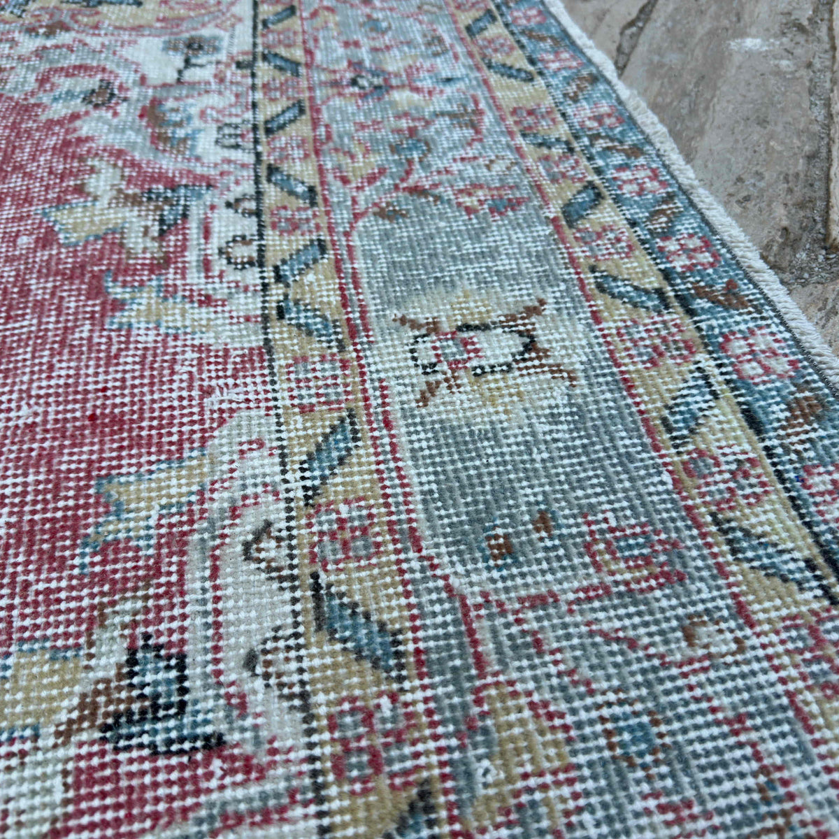 Close-up of the red vintage turkish rug showing medallion details, hand-knotted weave, wool and cotton and low pile.