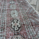 Close-up of the red vintage turkish rug showing floral details, hand-knotted weave, wool and cotton and low pile.