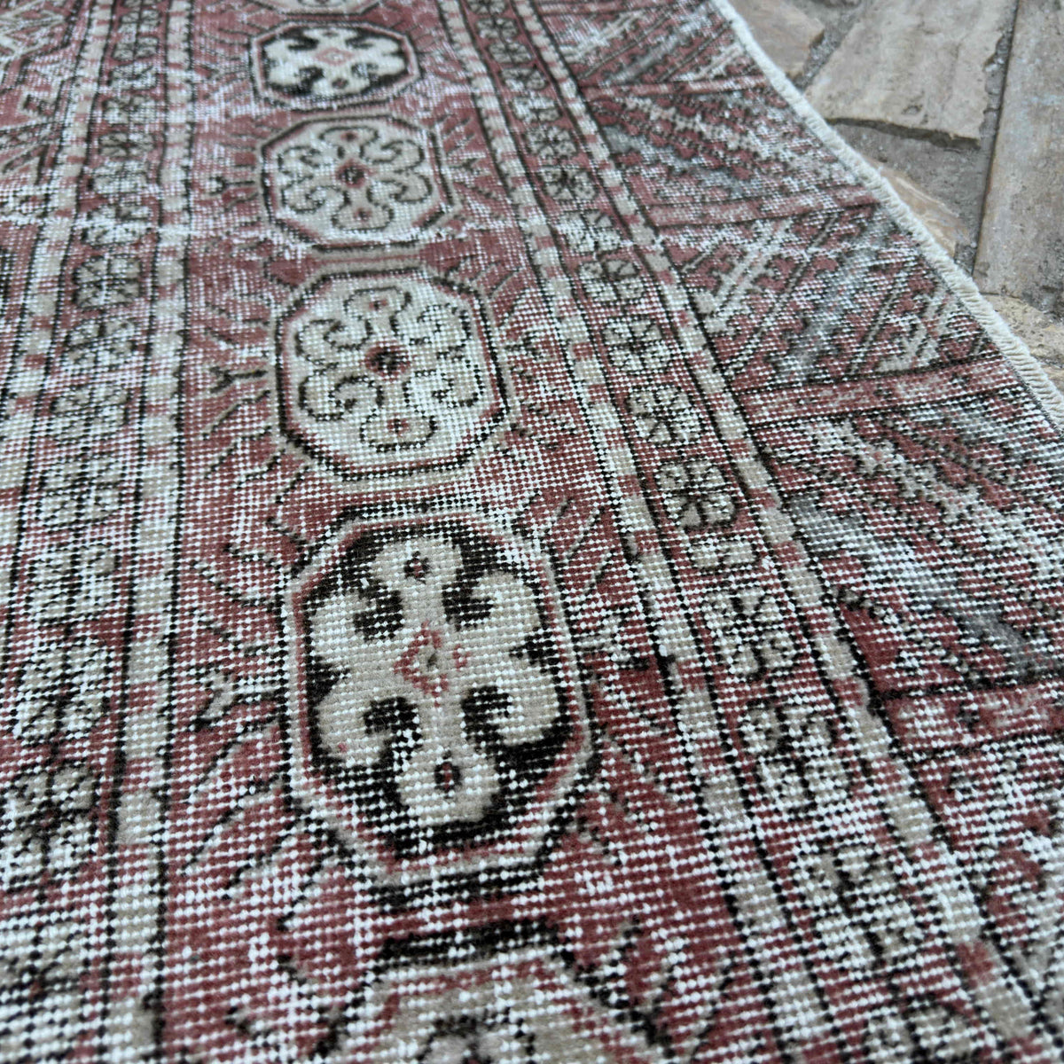 Close-up of the red vintage turkish rug showing floral details, hand-knotted weave, wool and cotton and low pile.