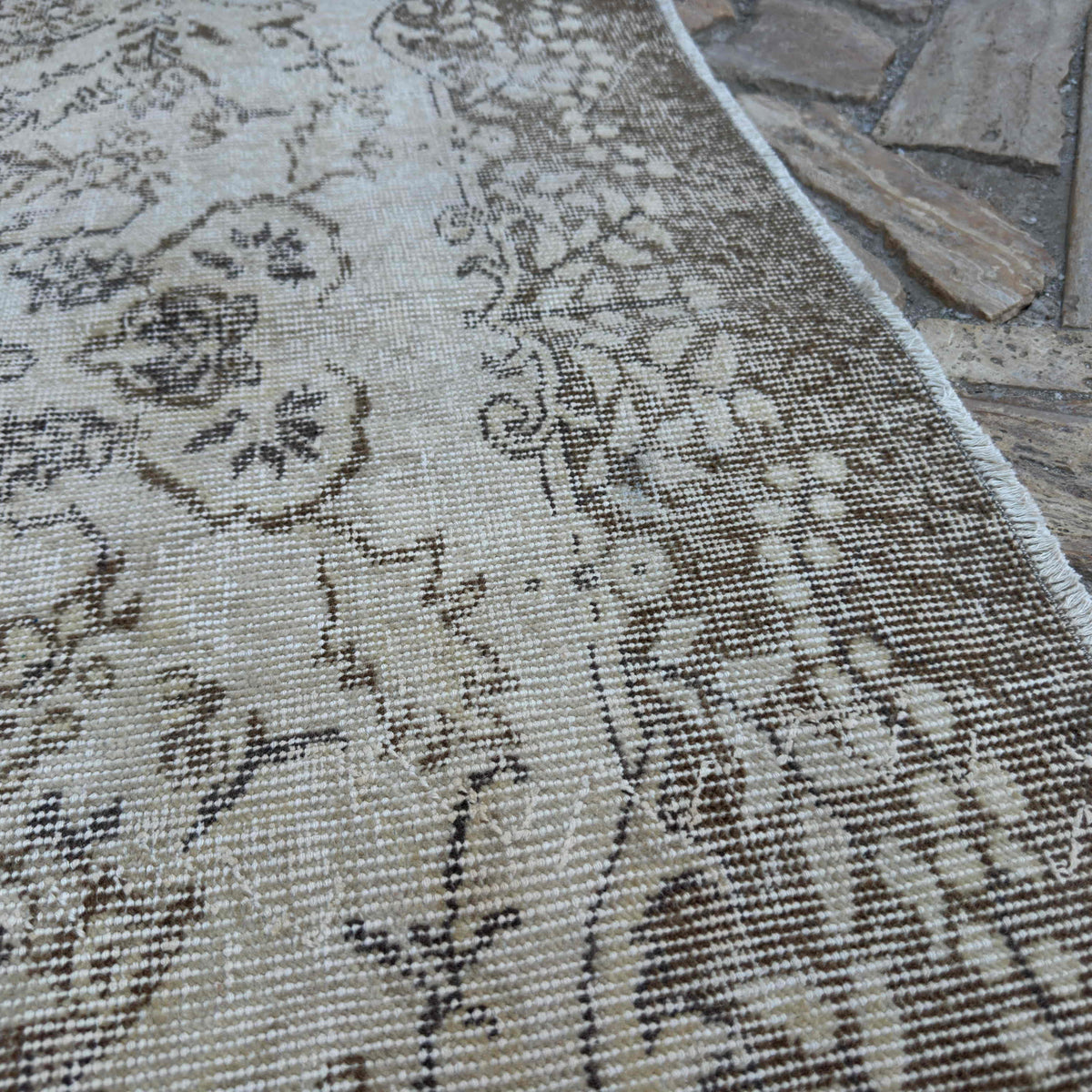 Close-up of the beige vintage turkish rug showing neutral details, hand-knotted weave, wool and cotton and low pile.