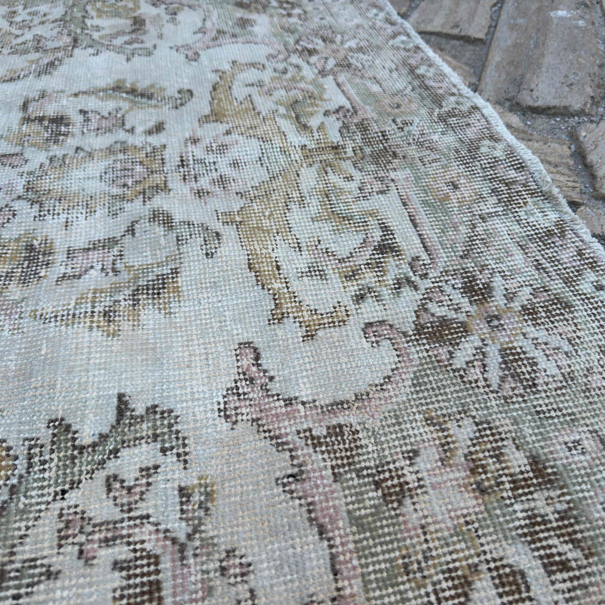 Close-up of the beige vintage turkish rug showing traditional details, hand-knotted weave, wool and cotton and low pile.