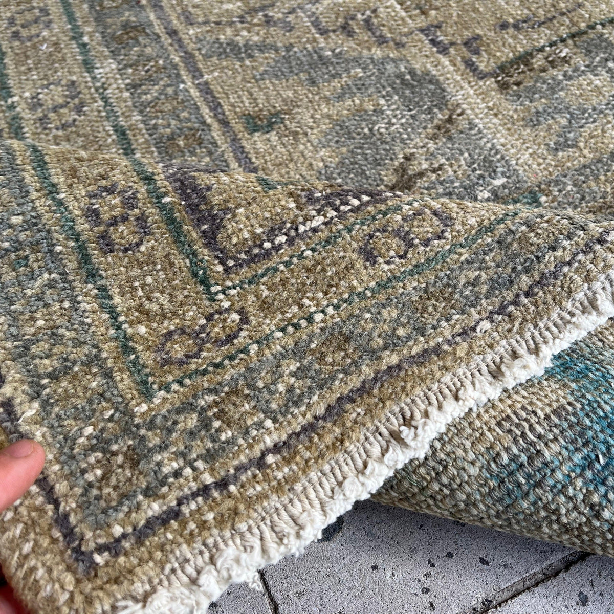 Close-up of the beige vintage turkish rug showing traditional details, hand-knotted weave, wool and cotton and low pile.