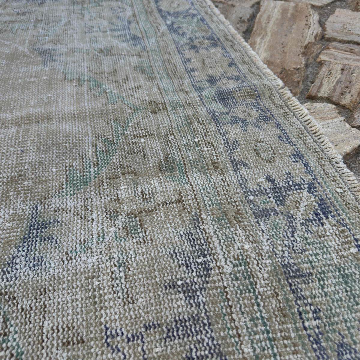 Close-up of the beige vintage turkish rug showing neutral details, hand-knotted weave, wool and cotton and low pile.