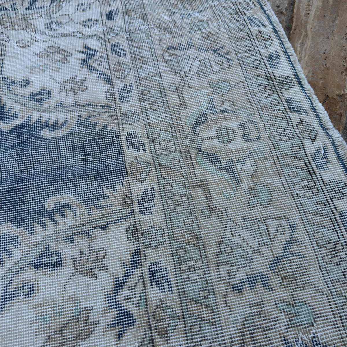 Close-up of the beige vintage turkish rug showing neutral and medallion details, hand-knotted weave, wool and cotton and low pile.