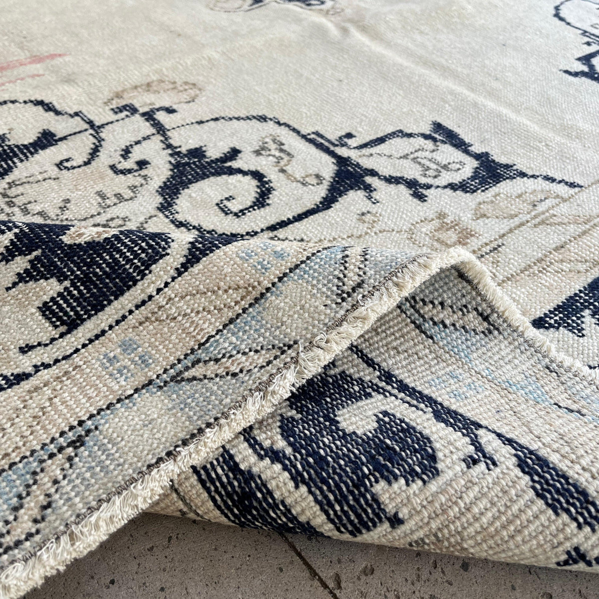 Close-up of the blue vintage turkish rug showing neutral details, hand-knotted weave, wool and cotton and low pile.