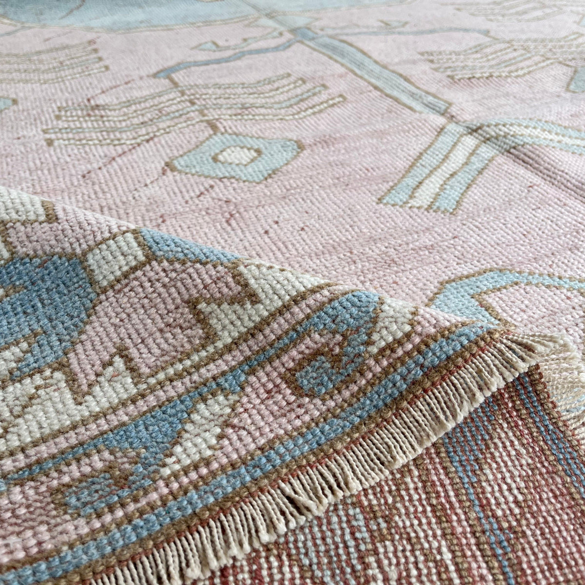 Close-up of the pink vintage turkish rug showing medallion details, hand-knotted weave, wool and cotton and low pile.