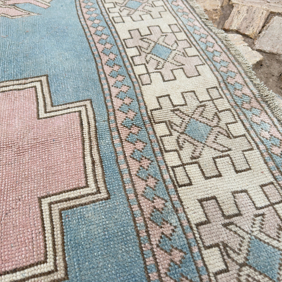 Close-up of the pink vintage turkish rug showing medallion details, hand-knotted weave, wool and cotton and low pile.