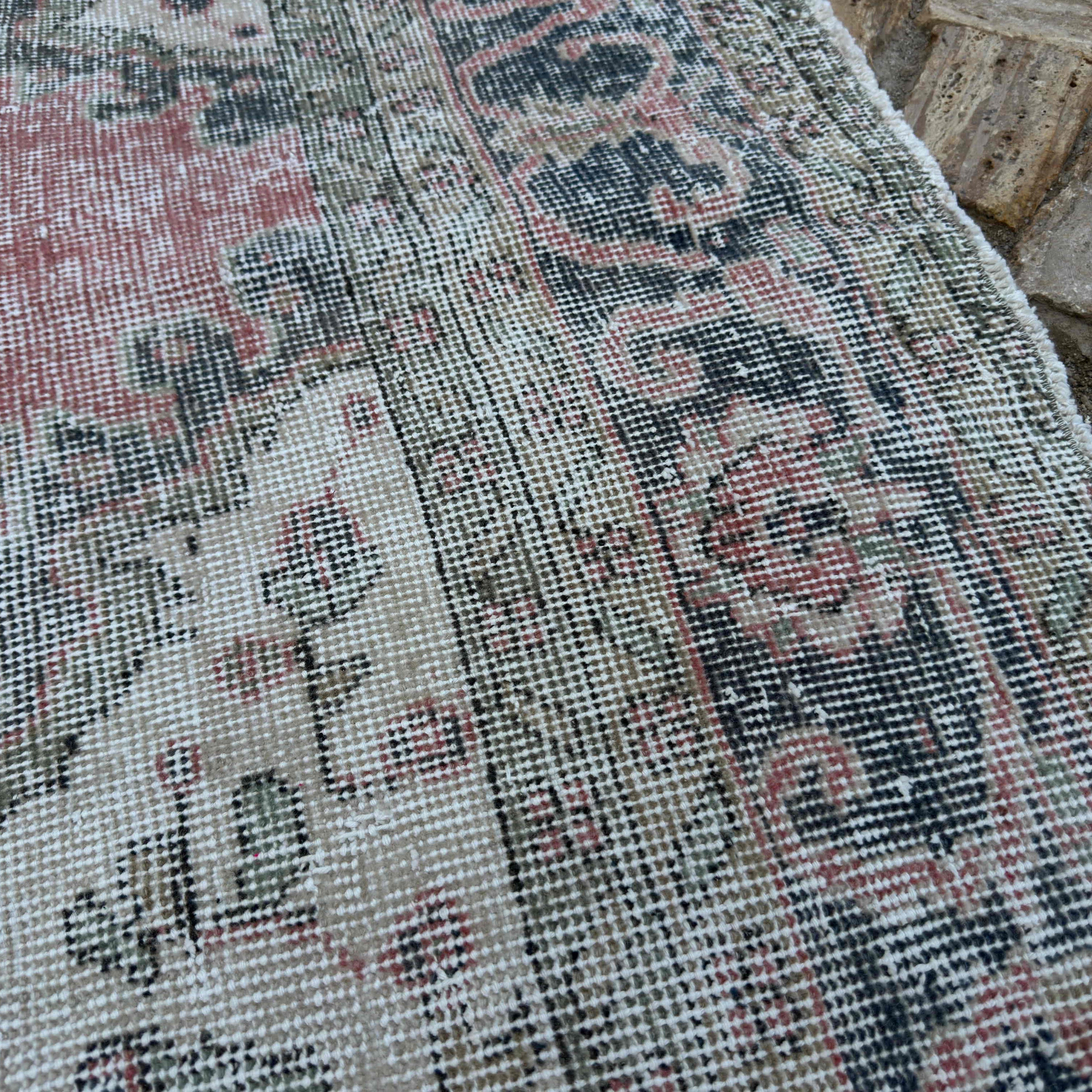 Close-up of the pink vintage turkish rug showing medallion details, hand-knotted weave, wool and cotton and low pile.