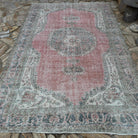 Pink 7' x 11' vintage turkish rug in wool and cotton, shown on the floor.