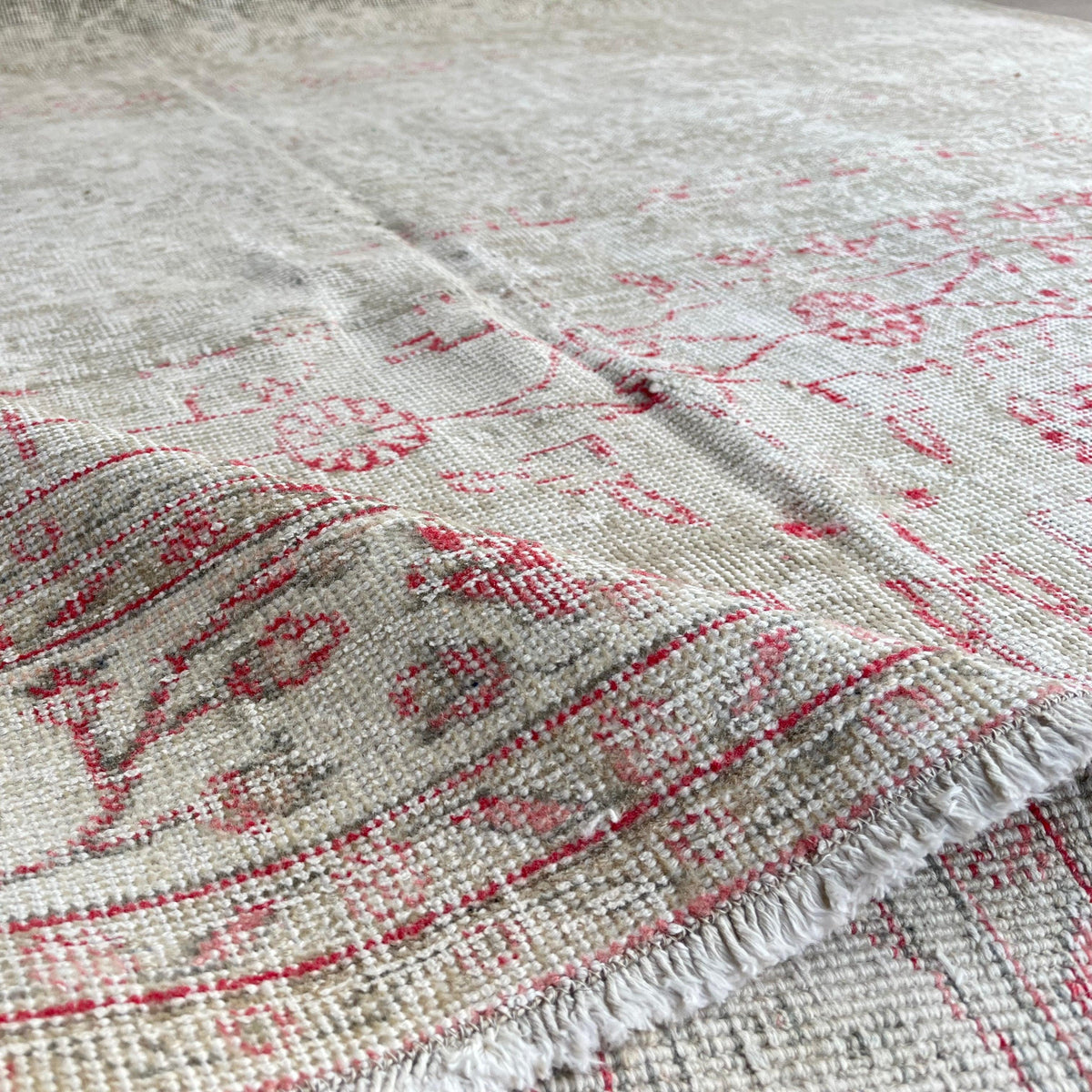 Close-up of the beige vintage turkish rug showing floral details, hand-knotted weave, wool and cotton and low pile.