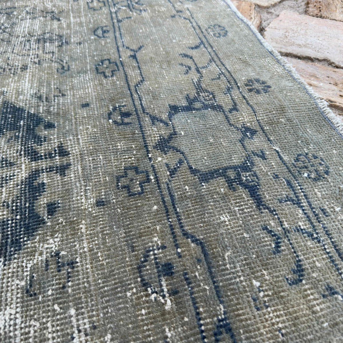 Close-up of the gray vintage turkish rug showing medallion details, hand-knotted weave, wool and cotton and low pile.