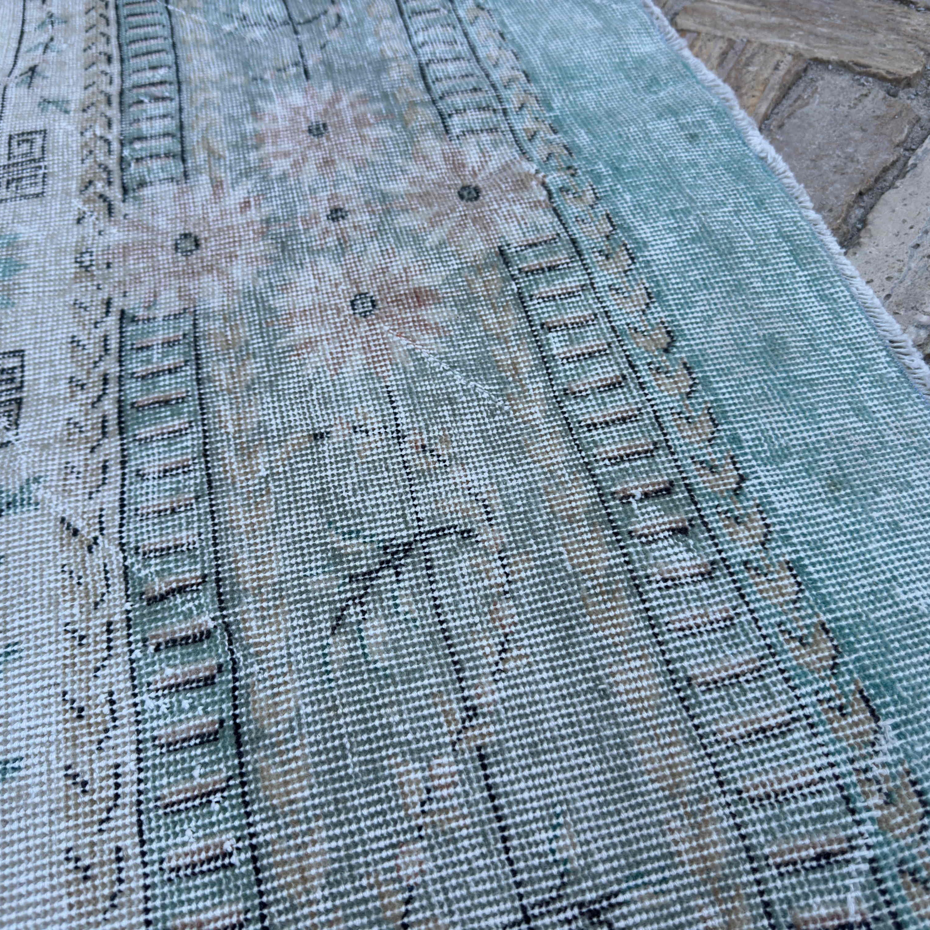 Close-up of the green vintage turkish rug showing medallion details, hand-knotted weave, wool and cotton and low pile.