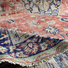 Close-up of the pale red vintage turkish rug showing medallion details, hand-knotted weave, wool and cotton and low pile.