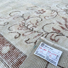 Close-up of the beige vintage turkish rug showing neutral and medallion details, hand-knotted weave, wool and cotton and low pile.