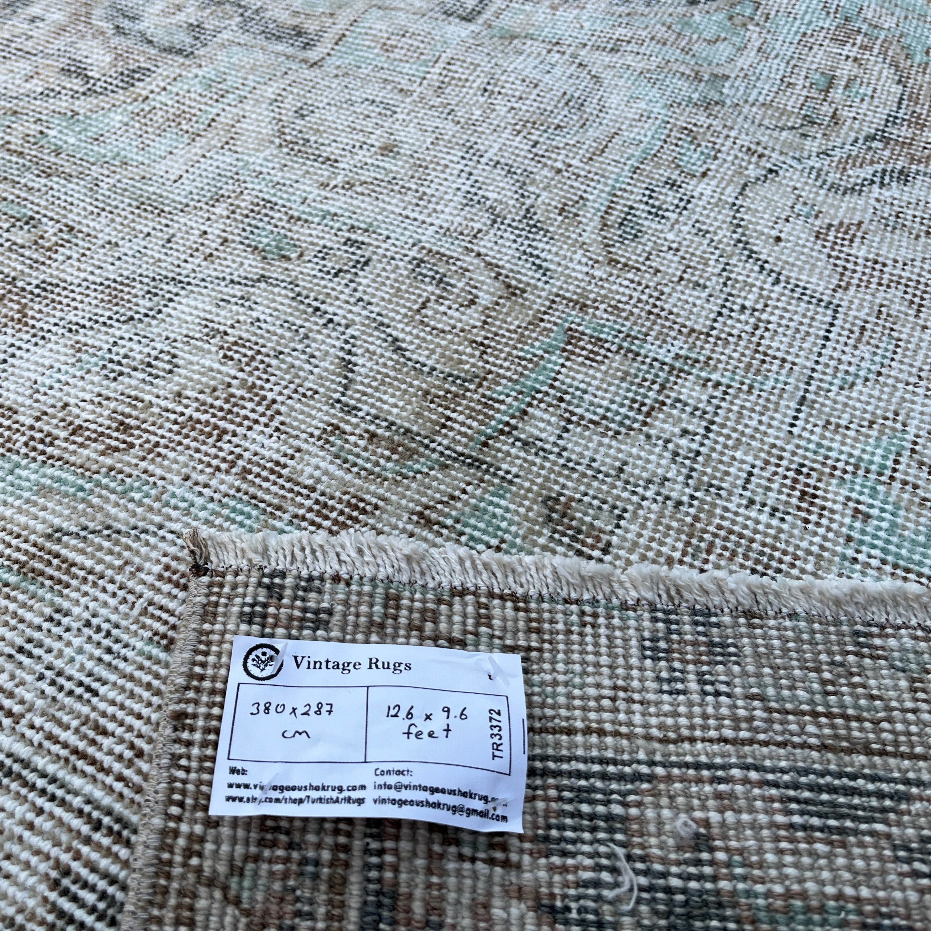 Close-up of the beige vintage turkish rug showing neutral and medallion details, hand-knotted weave, wool and cotton and low pile.