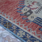 Red 2' x 5' vintage turkish rug in wool and cotton, shown on the floor.