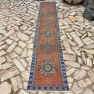 Orange 2' x 11' vintage turkish runner rug in wool and cotton, shown on the floor.